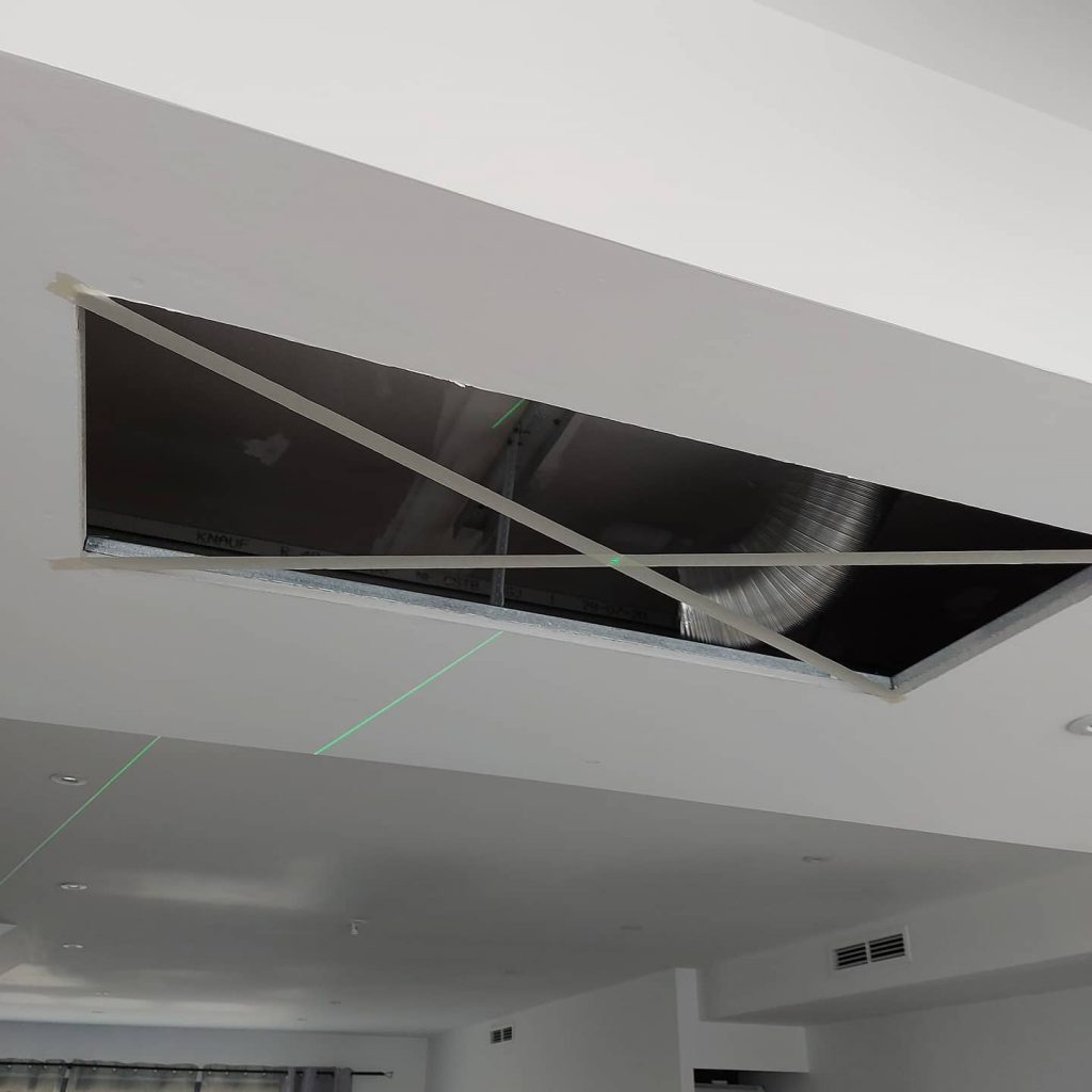 Pose d'une hotte encastrée dans le plafond.